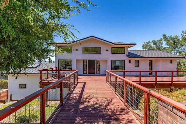 back of property featuring metal roof, a standing seam roof, and a wooden deck