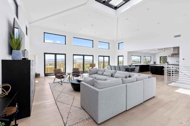 living area featuring light wood-style flooring, visible vents, coffered ceiling, and beamed ceiling