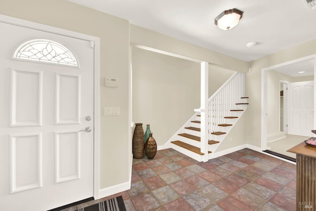 foyer with stone finish flooring, stairway, and baseboards