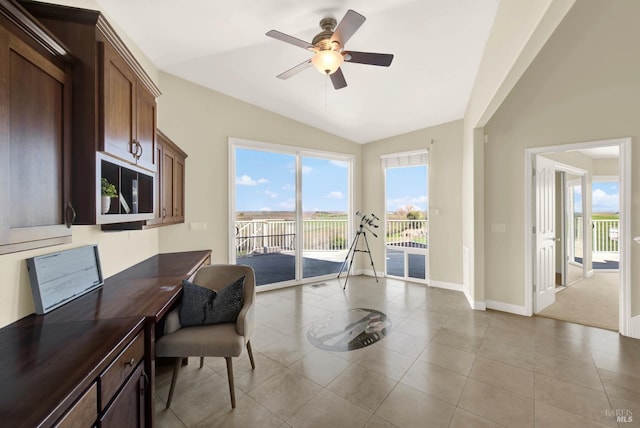 tiled office space with lofted ceiling, a ceiling fan, and baseboards