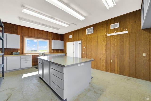 kitchen featuring visible vents, wooden walls, and white cabinetry