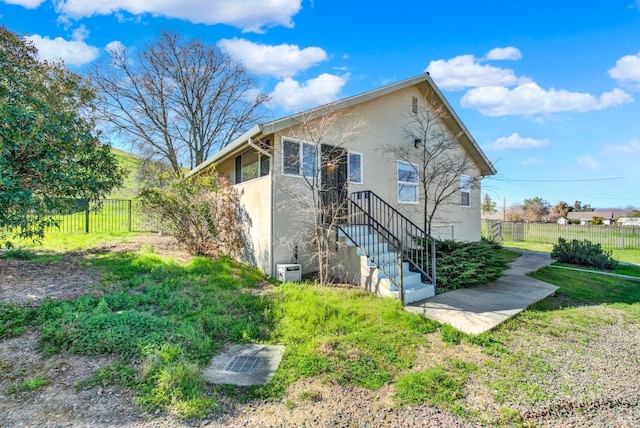 back of house with a yard, fence, and stucco siding