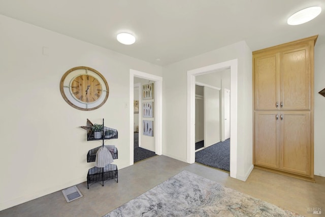 hall featuring finished concrete floors and visible vents