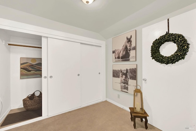 interior space featuring vaulted ceiling, a closet, and light colored carpet