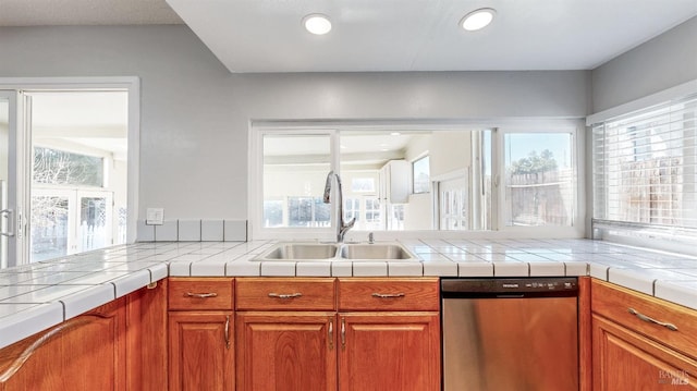 kitchen featuring stainless steel dishwasher, brown cabinetry, plenty of natural light, and a sink