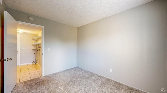 empty room with a textured ceiling, carpet flooring, and tile patterned floors