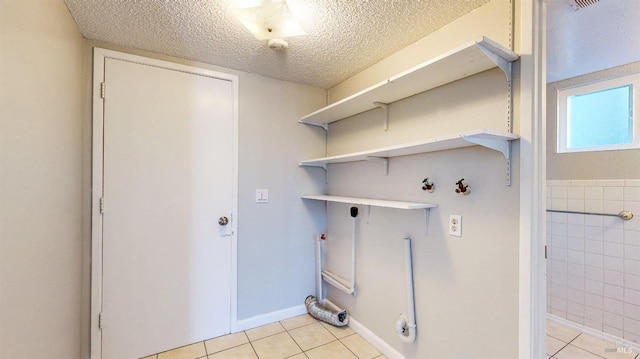 clothes washing area featuring laundry area, hookup for a washing machine, light tile patterned floors, and a textured ceiling