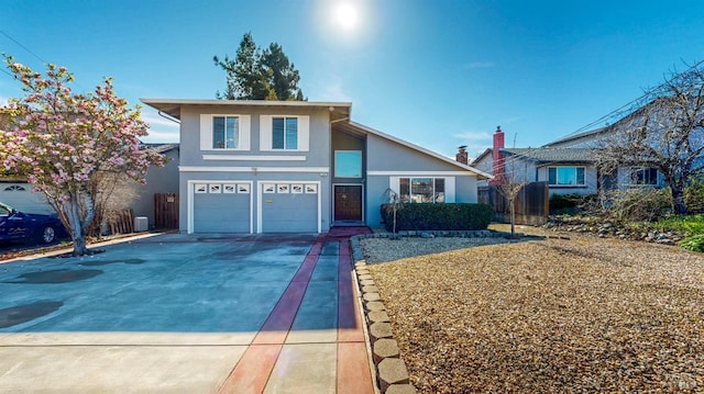 view of front facade with driveway, a garage, fence, central AC, and stucco siding