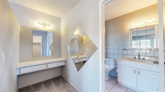 bathroom featuring toilet, tile patterned floors, a textured ceiling, vanity, and tile walls