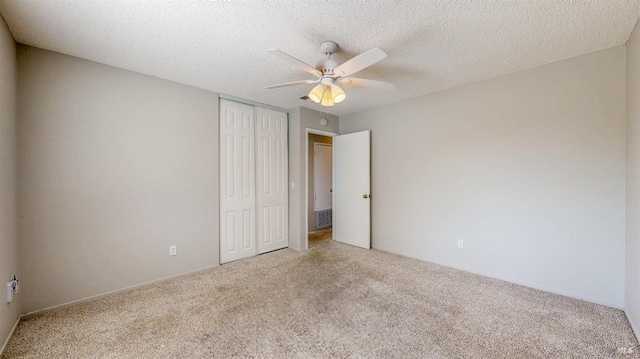 unfurnished bedroom featuring a textured ceiling, ceiling fan, a closet, and carpet flooring