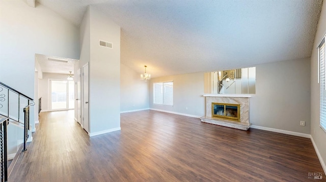 unfurnished living room with visible vents, a high end fireplace, wood finished floors, baseboards, and stairs