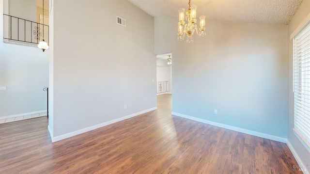 unfurnished room featuring baseboards, a textured ceiling, visible vents, and wood finished floors