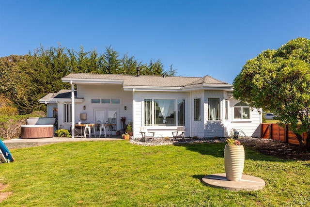 rear view of property with a patio area, a lawn, a hot tub, and fence