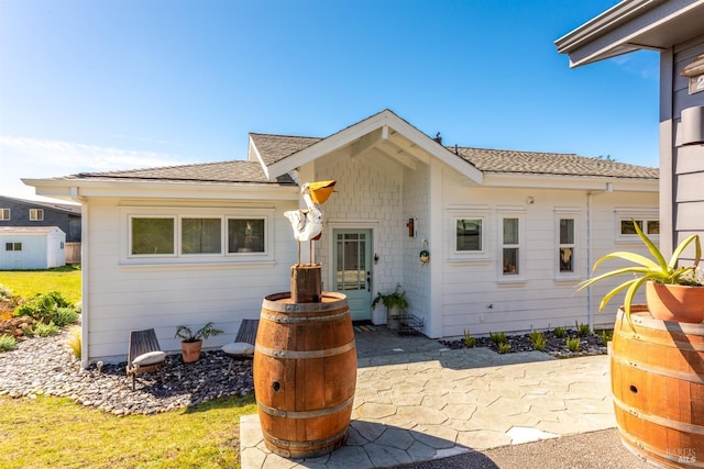 view of front of home featuring roof with shingles and a patio area