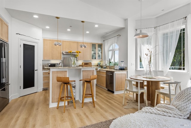 kitchen featuring glass insert cabinets, a kitchen island with sink, light wood-style floors, and light brown cabinetry