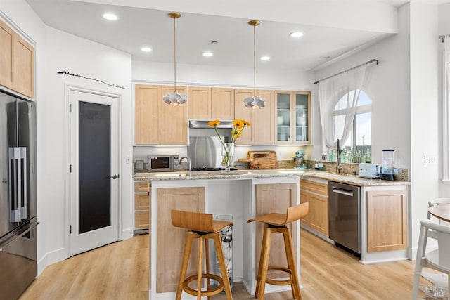 kitchen with stainless steel appliances, recessed lighting, light wood-style flooring, light brown cabinetry, and an island with sink