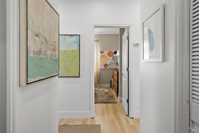 corridor with light wood-style flooring and baseboards