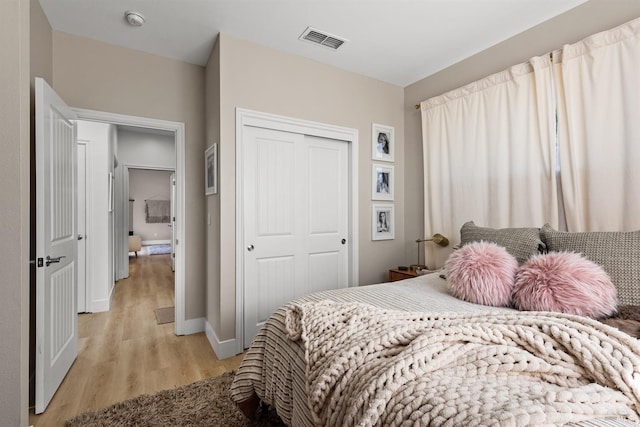 bedroom featuring a closet, visible vents, baseboards, and light wood finished floors