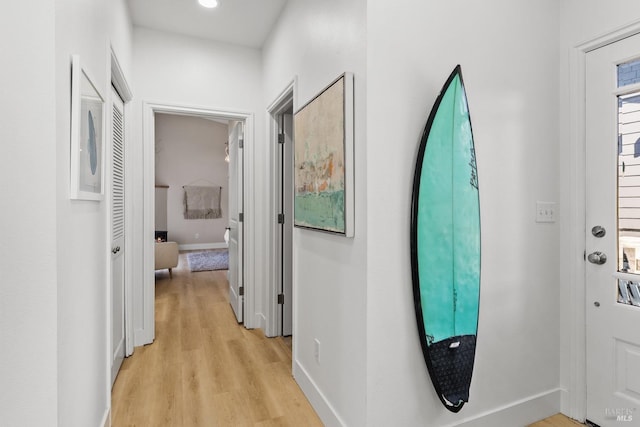 hall with baseboards and light wood-style floors