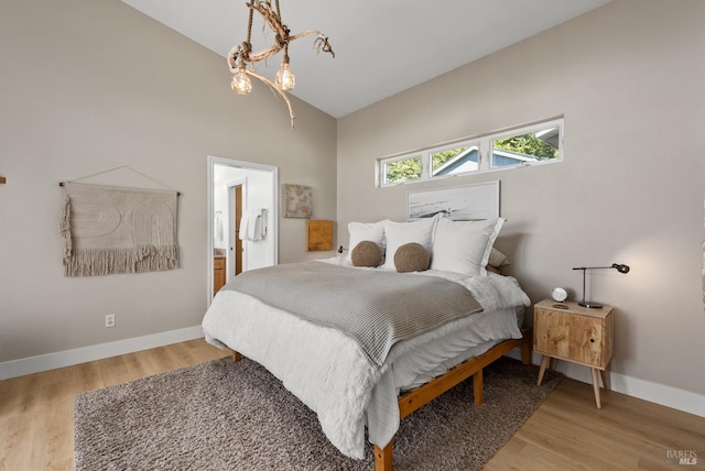 bedroom with light wood finished floors, baseboards, vaulted ceiling, and a chandelier