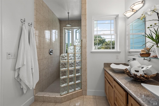 bathroom featuring tile patterned flooring, a sink, baseboards, double vanity, and walk in shower