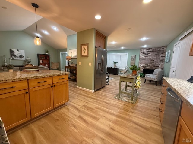 kitchen featuring decorative light fixtures, open floor plan, stainless steel appliances, light wood-style floors, and a fireplace