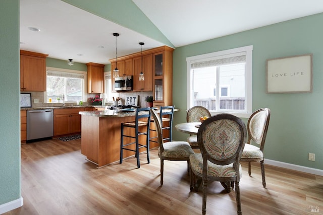 kitchen featuring decorative backsplash, a breakfast bar, glass insert cabinets, and stainless steel appliances