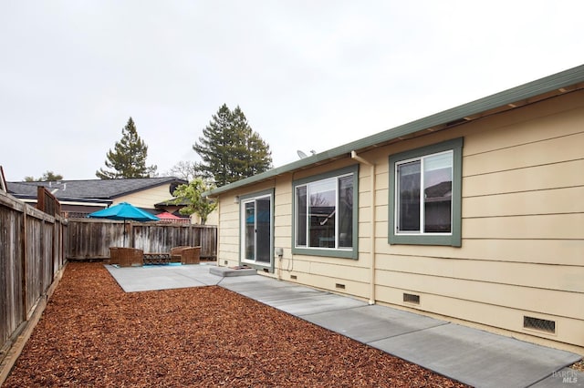 back of property with crawl space, a fenced backyard, and a patio