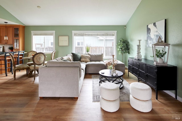 living area with vaulted ceiling, wood finished floors, and baseboards