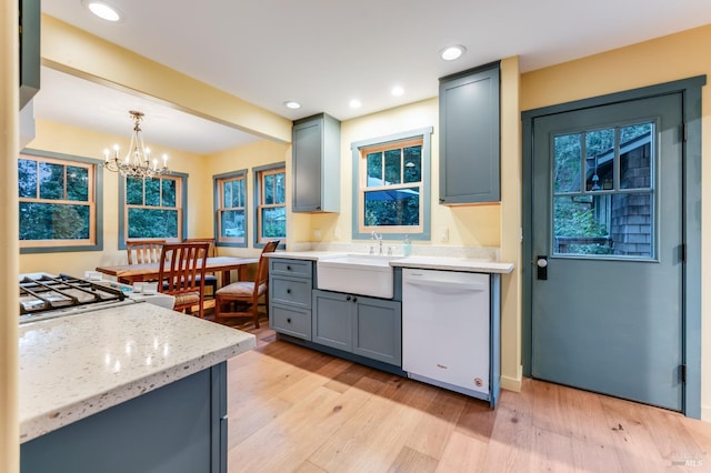 kitchen with light wood finished floors, white dishwasher, a sink, and gray cabinetry