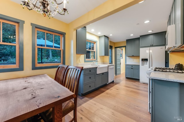 kitchen with white appliances, a sink, light wood-style flooring, and recessed lighting