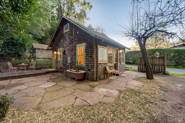 view of home's exterior with fence, a deck, and a patio