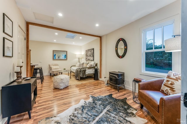 living area featuring a wood stove, light wood-style floors, attic access, and recessed lighting