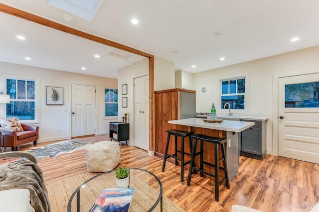 living room with light wood-type flooring, a skylight, baseboards, and recessed lighting