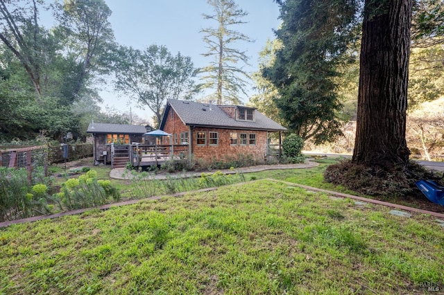 back of house with a yard, brick siding, a wooden deck, and fence