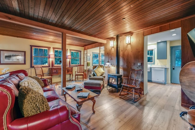 living area with a wood stove, light wood-style floors, wood ceiling, and beamed ceiling