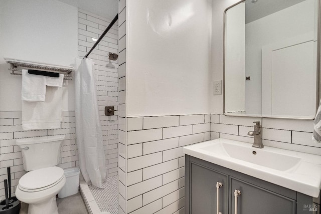 bathroom with toilet, tiled shower, tile walls, and vanity