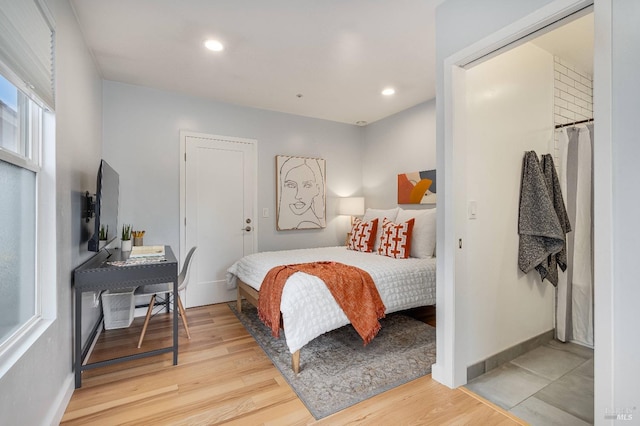 bedroom with light wood finished floors, multiple windows, baseboards, and recessed lighting