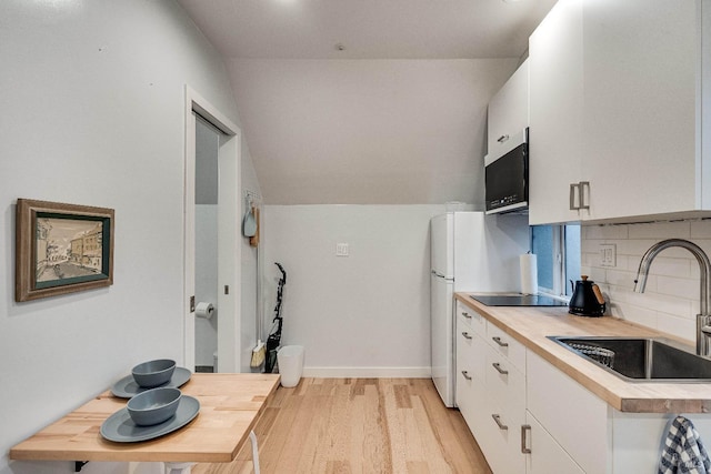 kitchen featuring white cabinets, a sink, light wood-type flooring, black appliances, and backsplash