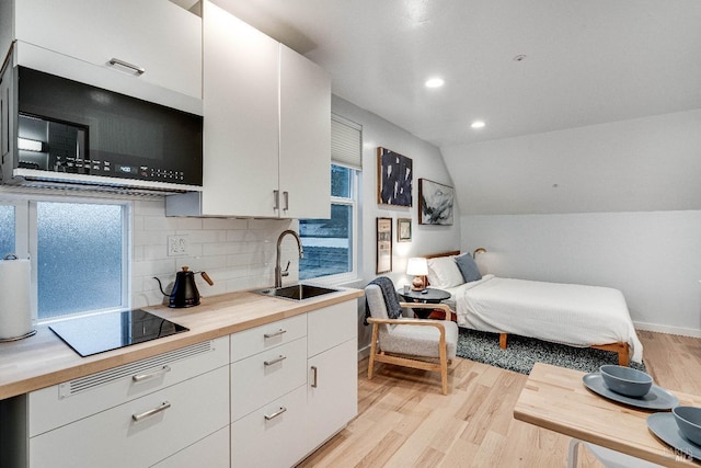 bedroom featuring light wood-type flooring, vaulted ceiling, a sink, and recessed lighting