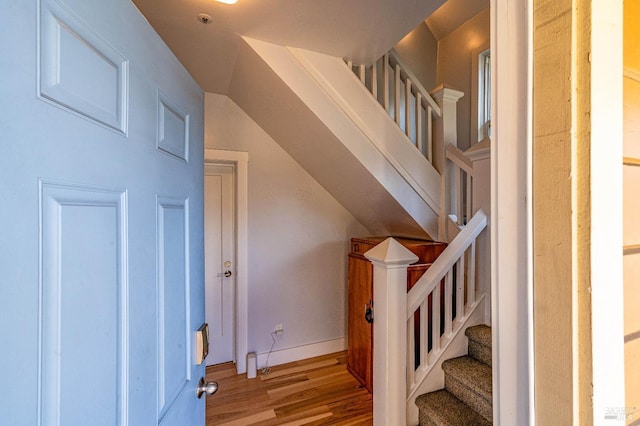 stairway with lofted ceiling, baseboards, and wood finished floors