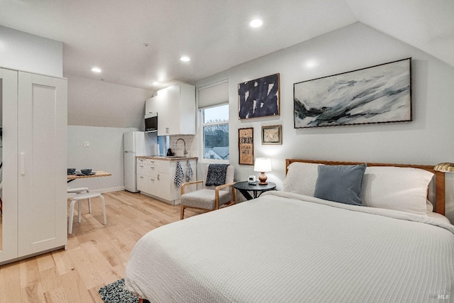 bedroom with lofted ceiling, recessed lighting, a sink, light wood-style floors, and freestanding refrigerator