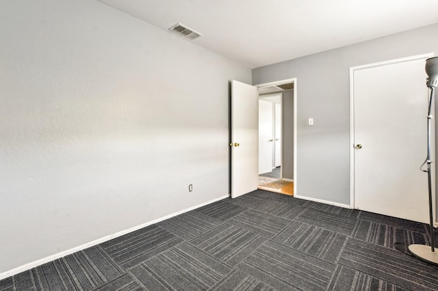 unfurnished bedroom featuring dark colored carpet, visible vents, and baseboards