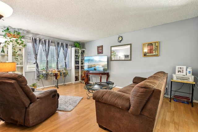 living room with baseboards, a textured ceiling, and light wood-style flooring