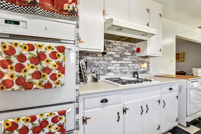 kitchen with under cabinet range hood, white appliances, white cabinetry, and light countertops