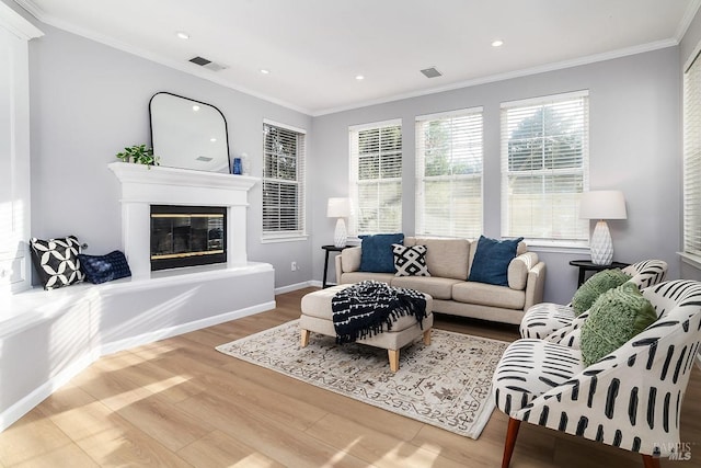 living room with crown molding, recessed lighting, visible vents, a glass covered fireplace, and wood finished floors