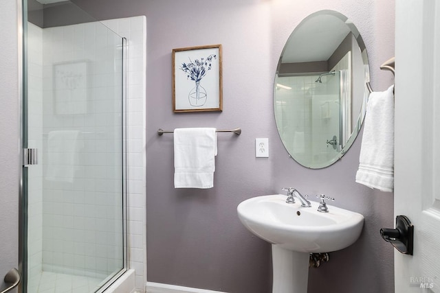 full bath featuring a shower stall and baseboards