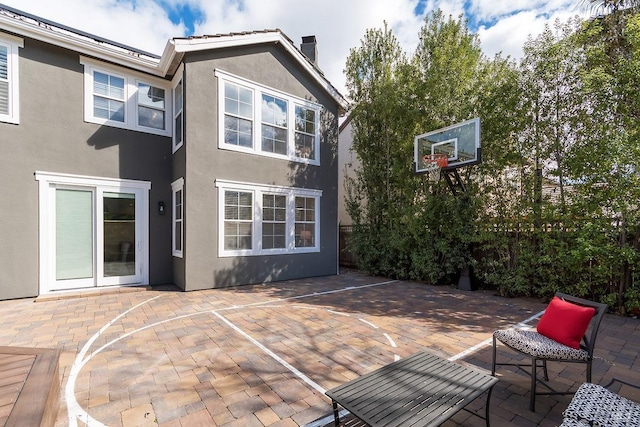 exterior space featuring a patio, a chimney, and stucco siding