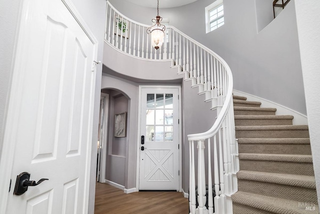 entrance foyer with a wealth of natural light, a towering ceiling, baseboards, and wood finished floors