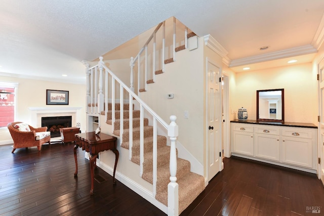 stairs featuring ornamental molding, recessed lighting, wood-type flooring, and a fireplace